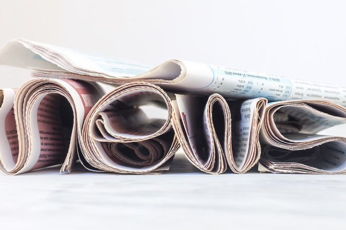 Someone has arranged a stack of newspapers to loosely resemble the letters n-e-w-s.