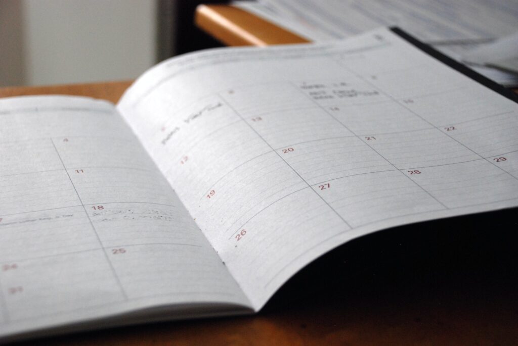 A monthly planner lies open on a desk with some notes in the margins.