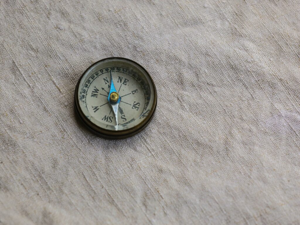 A compass pointing north lies atop a linen backdrop.